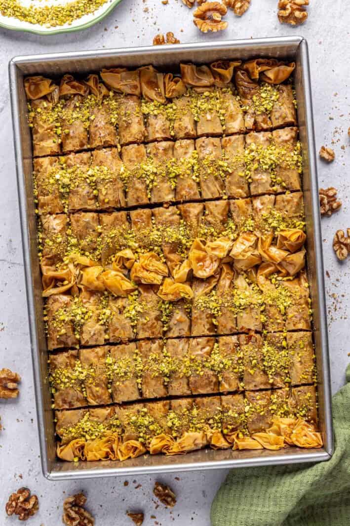 Best Baklava rolls in the baking dish garnished with crushed pistachios.