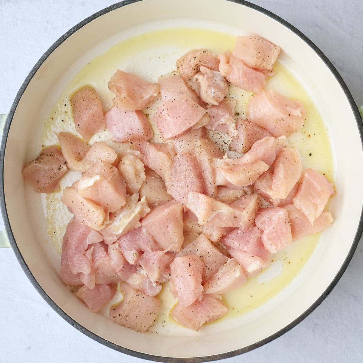 Seasoned chicken added to oiled pot before cooking it.