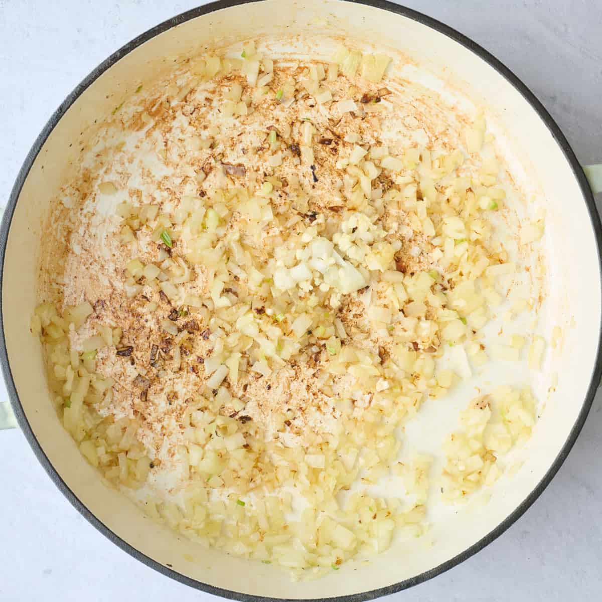 Chicken removed from the pot, with onions and garlic added and cooked in the same pot.