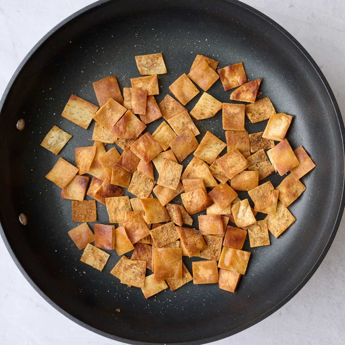 Pita bread pieces after toasting and seasoned with salt and pepper.