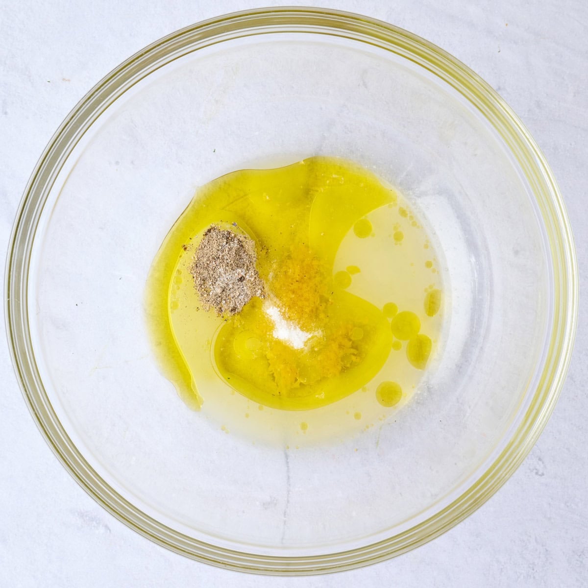 Olive oil, lemon zest and juice, salt and pepper in a large bowl before whisking.