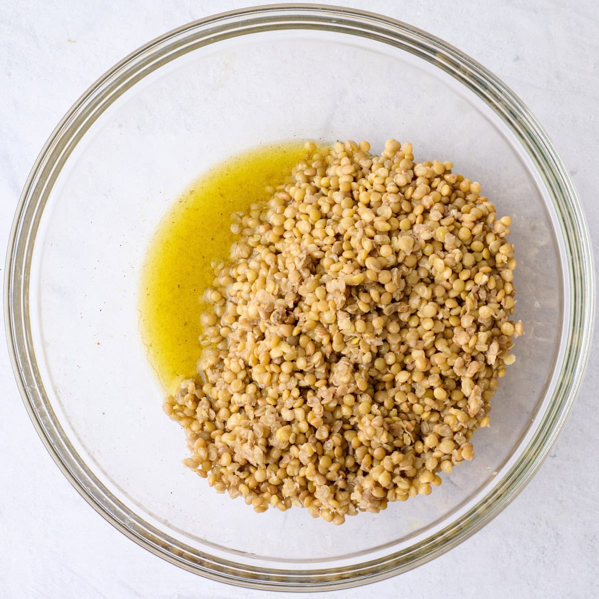 Cooked green lentils on top of salad dressing before tossing together.