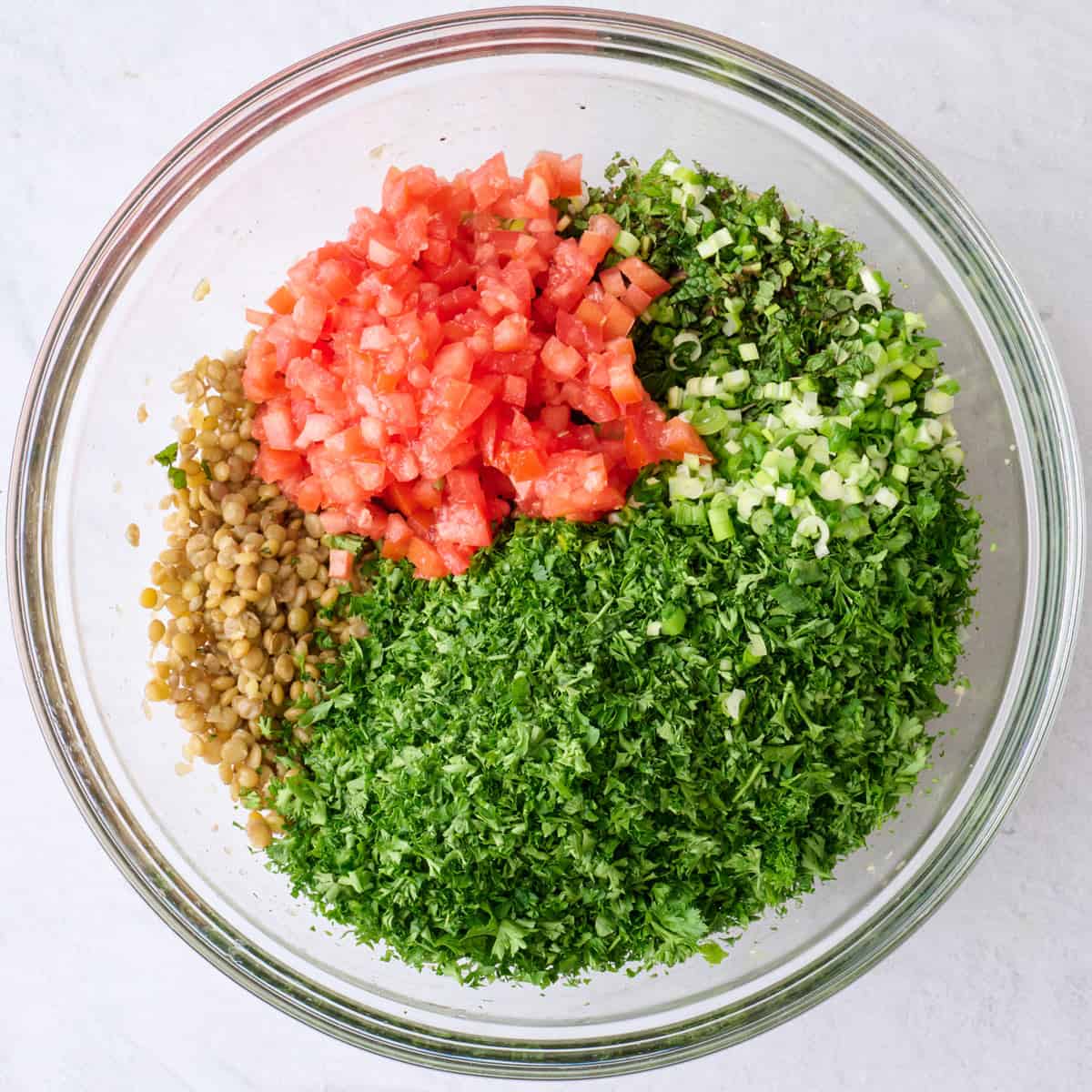 Chopped herbs and tomatoes added on top of lentils before combining.