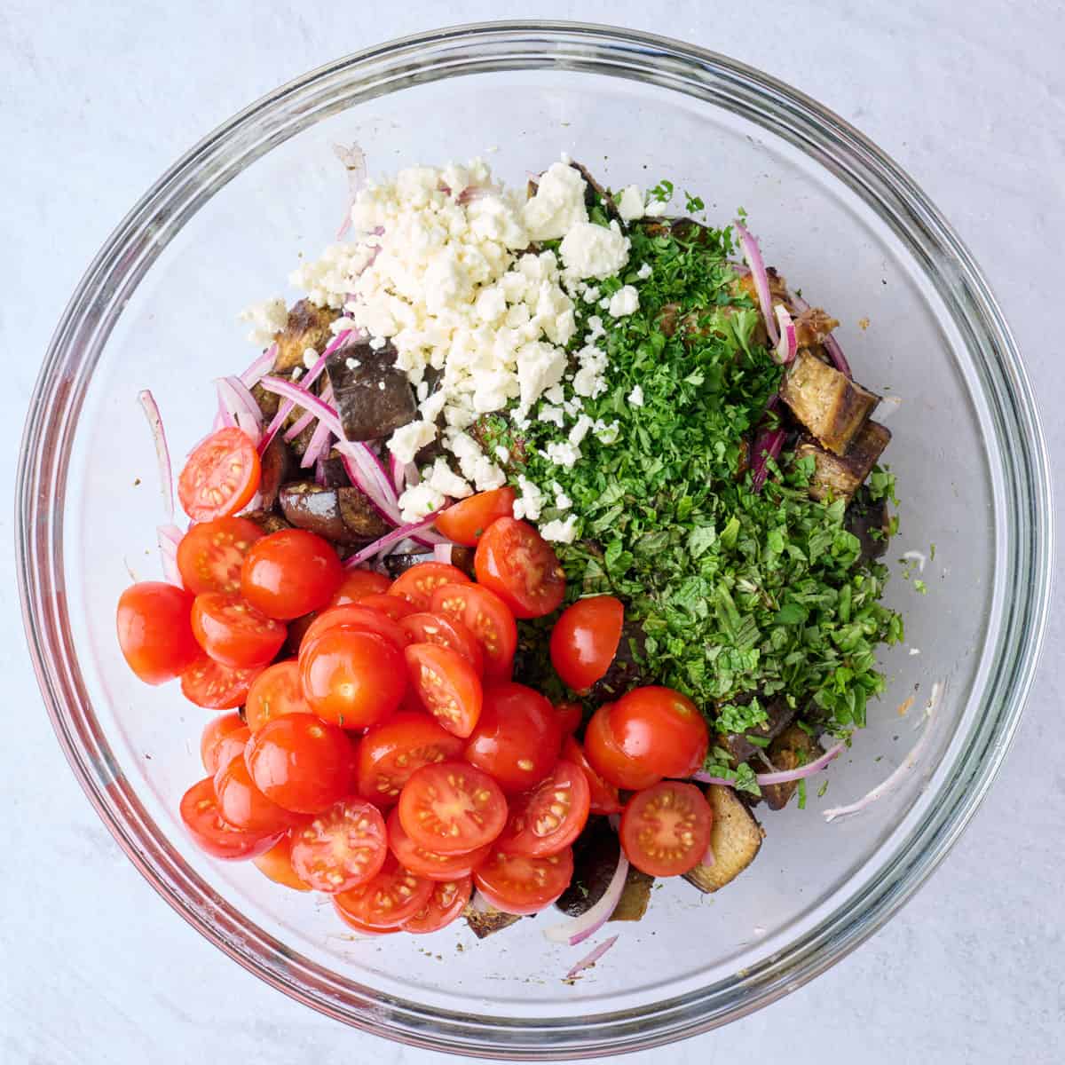 Cherry tomatoes, parsley, mint and feta added on top of eggplant before tossing.
