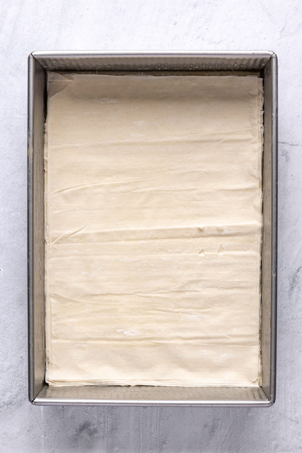 A stack of 20 phyllo sheets in a baking dish.