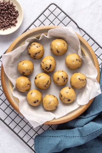 Chocolate chip protein balls without peanut butter in a wide shallow bowl with a small dish of extra chocolate chips nearby.