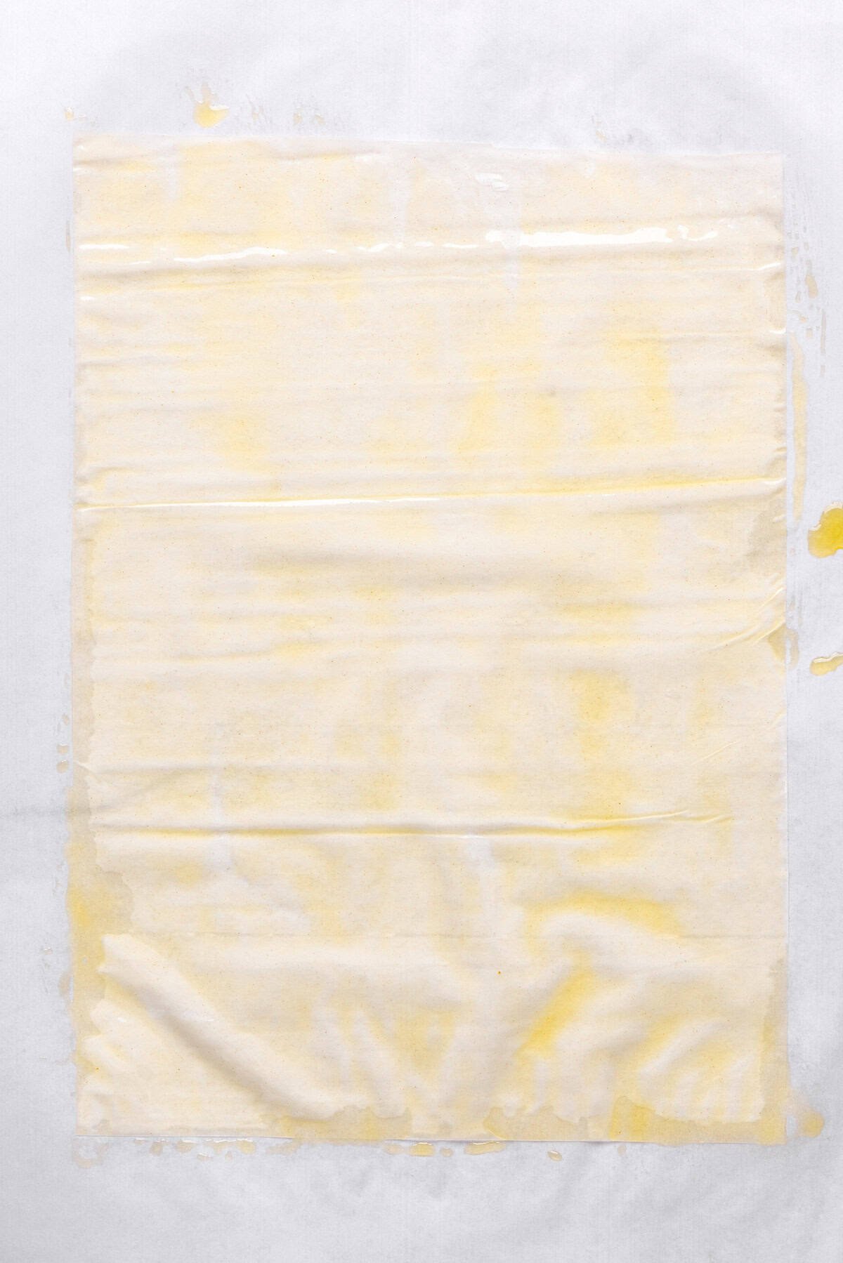 One sheet of phyllo on a flat surface with melted ghee brushed over it.