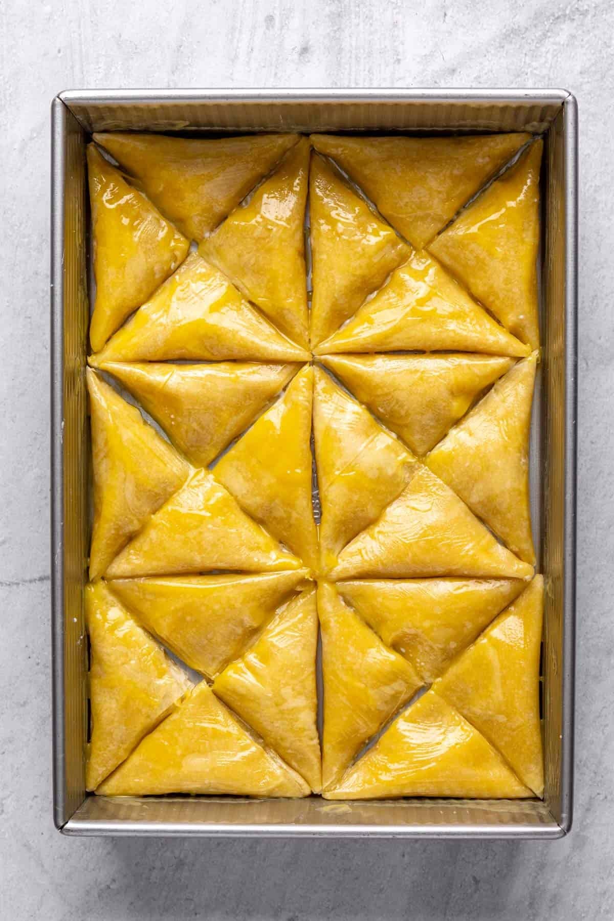 Folded phyllo on a baking dish with ghee brushed on top of it.