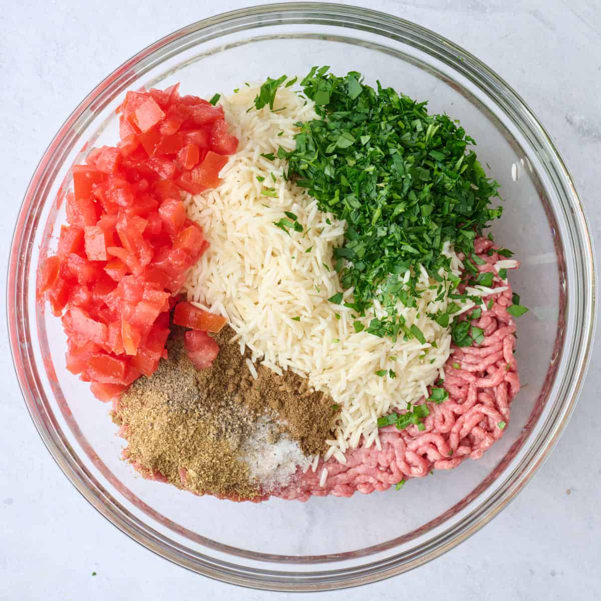Ground beef, rice, tomatoes, parsley, 7 spice, coriander, salt and pepper in a large bowl before combining.