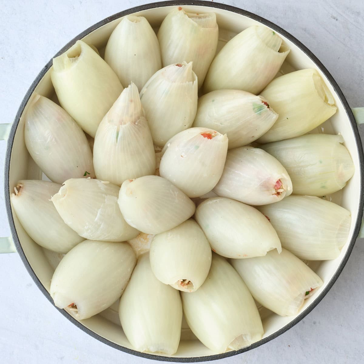 Onions filled with beef and rice mixture and arranged in an oven safe skillet.