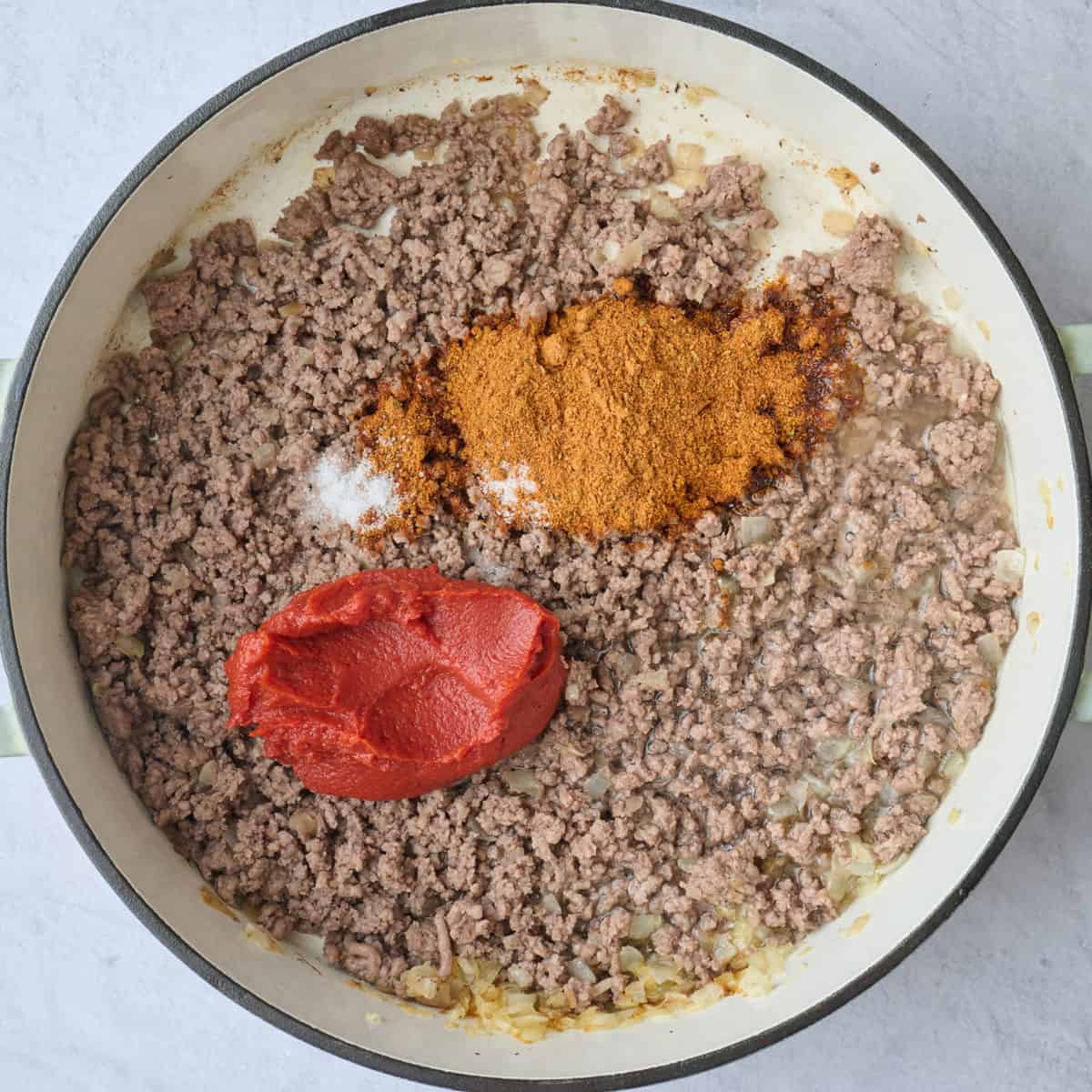 Ground beef after cooking with onions with taco seasoning, salt and tomato paste added.