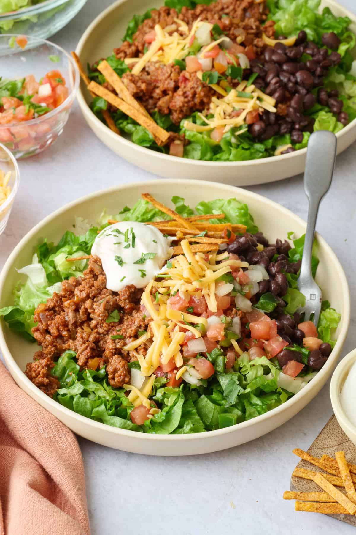Homemade taco salad bowlswith lettuce, ground beef taco meat, cheese, beans, pico de gallo, sour cream and tortilla strips.