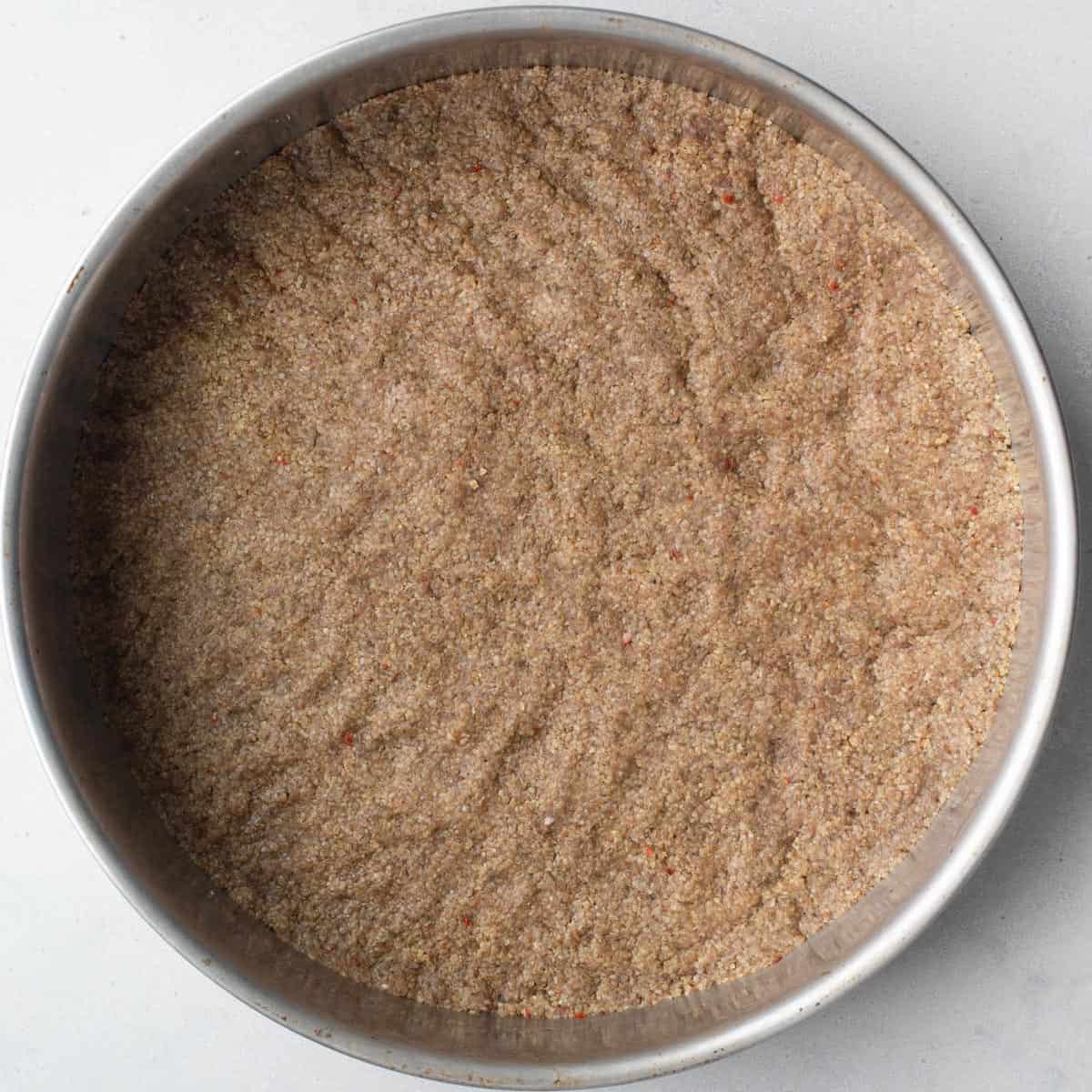 Beef and bulgur mixture for kibbeh pressed firmly into a round pan.