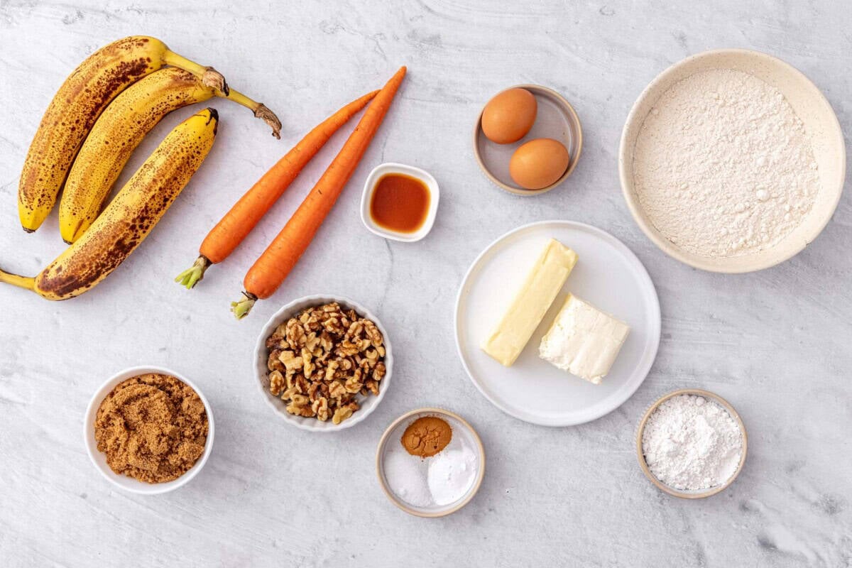 Ingredients for carrot banana bread recipe with cream cheese frosting: ripe bananas, carrots, vanilla, brown sugar, walnuts, eggs, butter, cream cheese, flour, powdered sugar, salt, baking powder, and cinnamon.