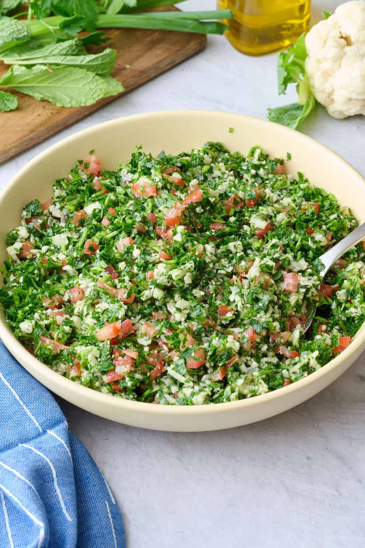 Best cauliflower rice tabbouleh salad recipe in a serving bowl made with fresh parsley, tomatoes, green onions, and mint.