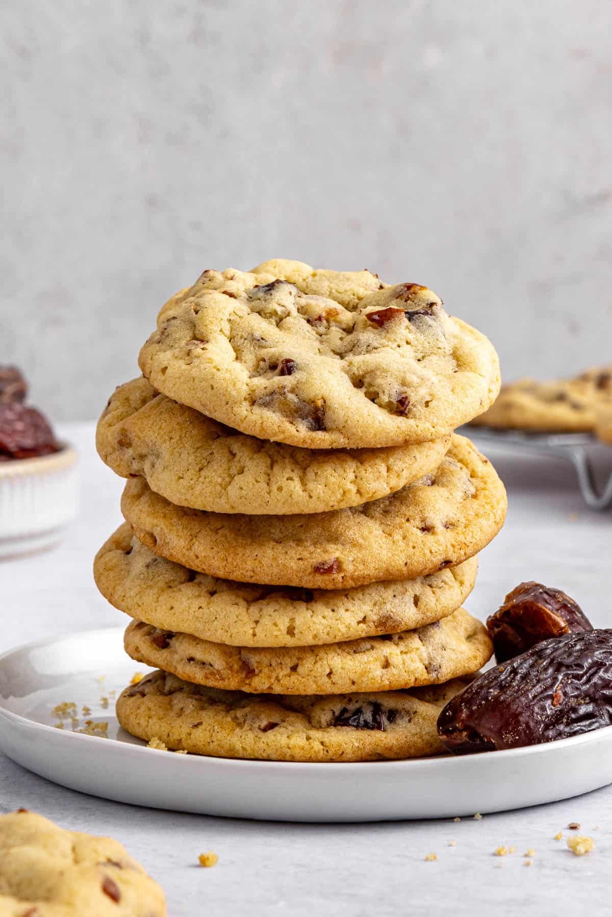 Best date cookies recipe stacked on a plate with a few extra whole Medjool dates nearby.