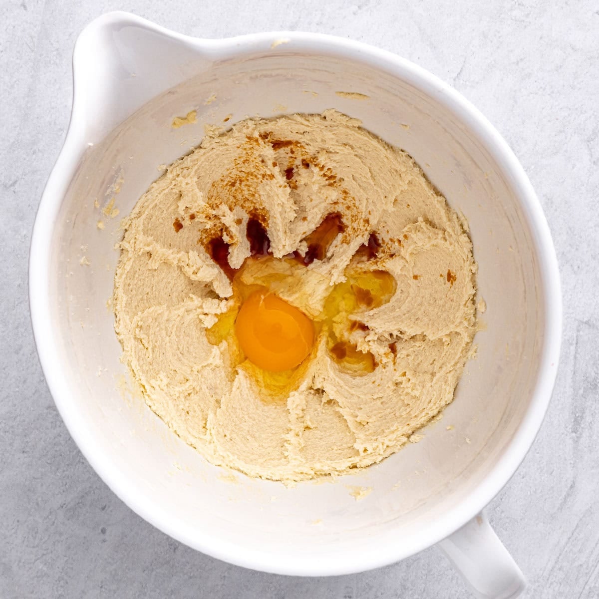 Creamed butter and sugar in a stand mixer bowl with vanilla and egg added before combining.