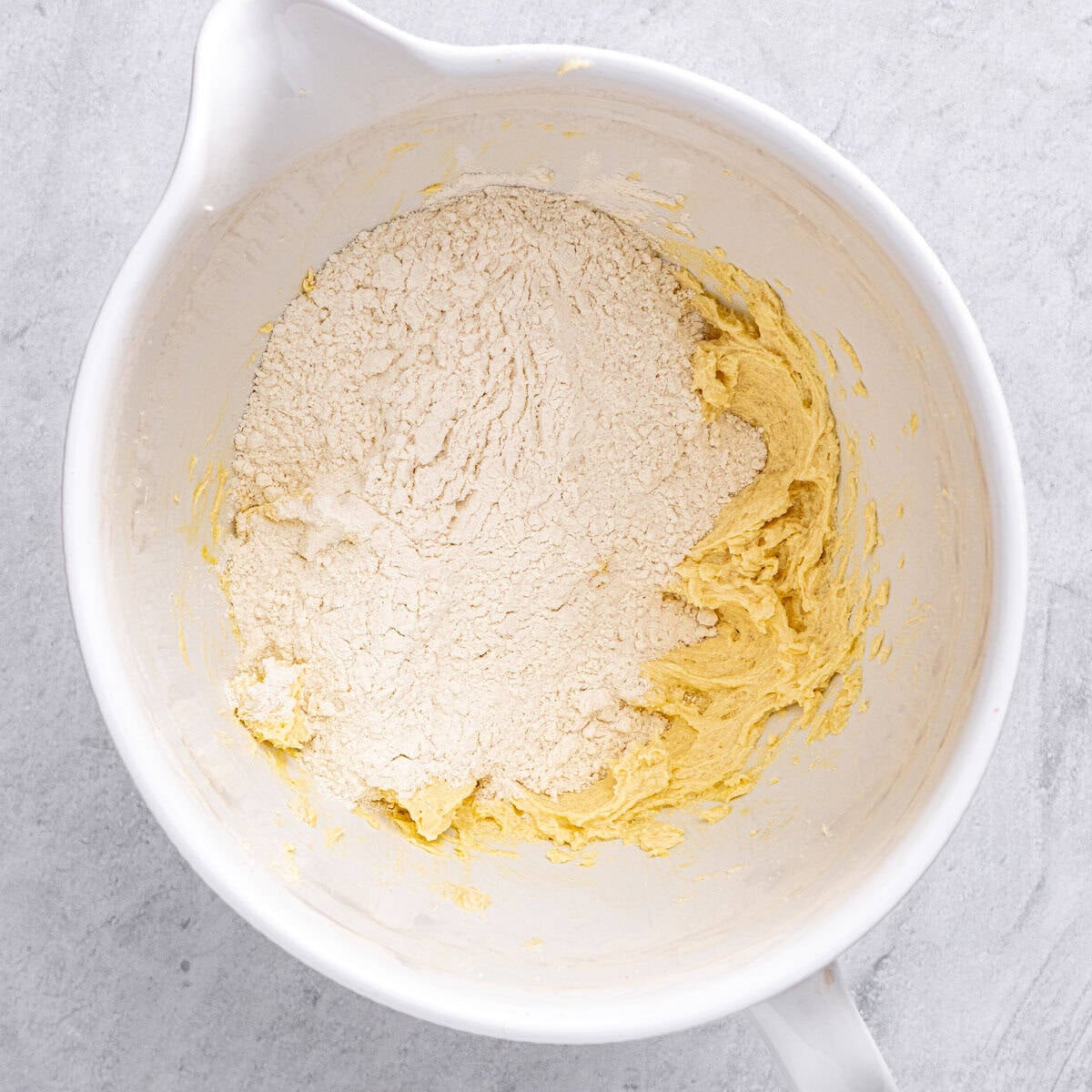 Flour added on top of wet ingredients in a bowl before folding together.