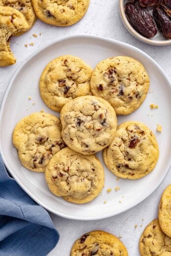 Easy chewy date cookies ono a plate with a small dish of more Medjool dates nearby.