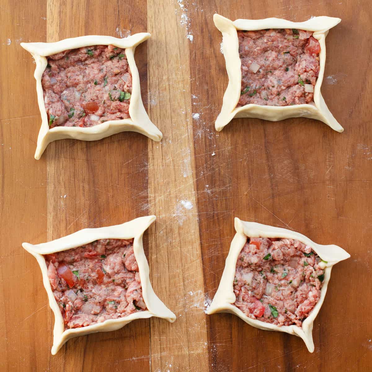 Meat pies after shaping around filling before baking.