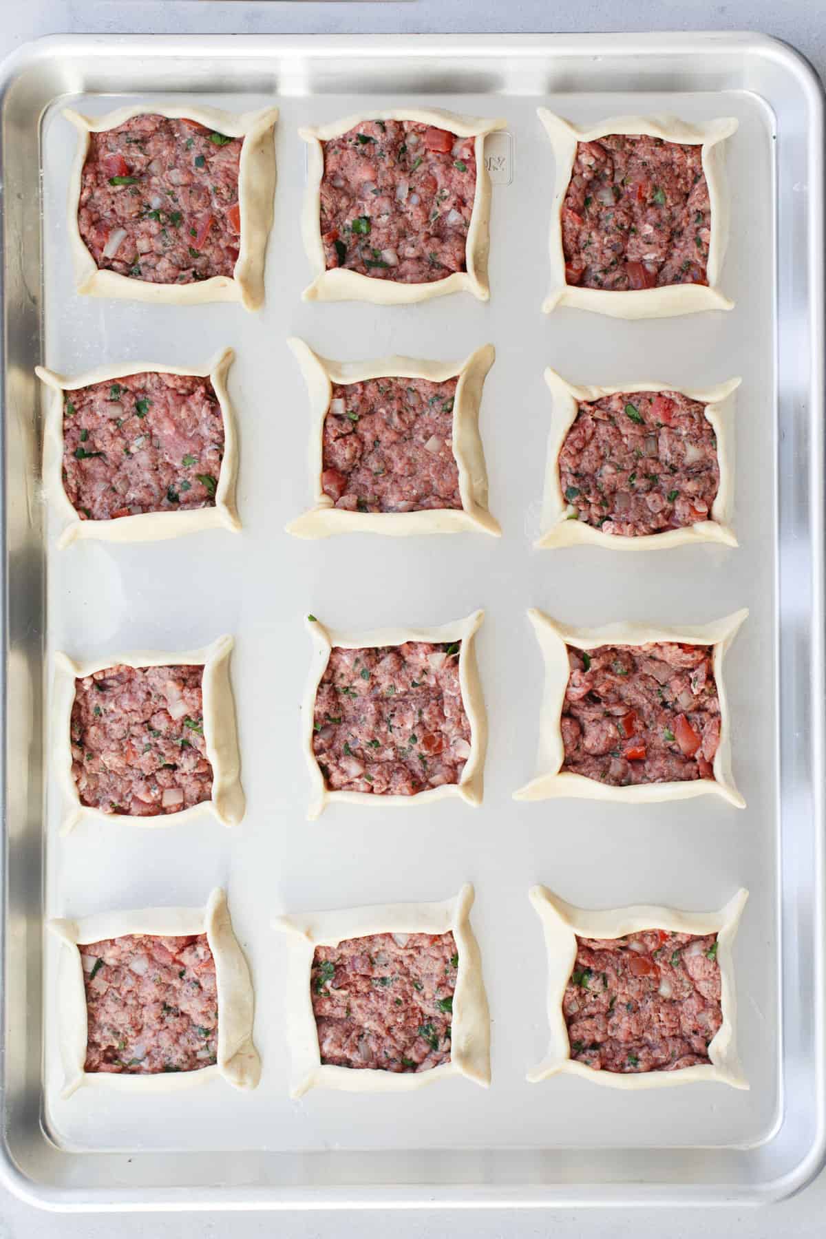 Lebanese sfeeha meat pie recipe on a baking sheet before baking.