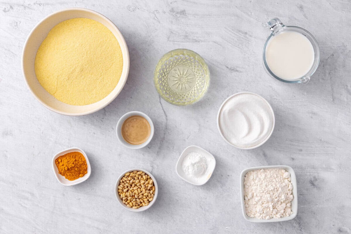 Ingredients for turmeric cake recipe: fine semolina flour, turmeric, pine nuts, tahini, oil, baking powder, sugar, flour, and milk.