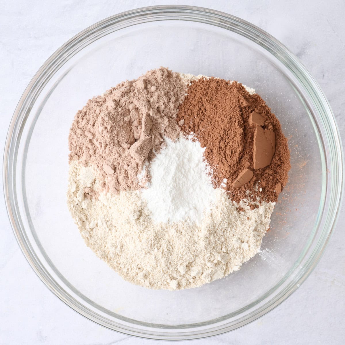 Ground rolled oats, chocolate protein powder, cocoa powder and baking powder in a bowl before whisking together.