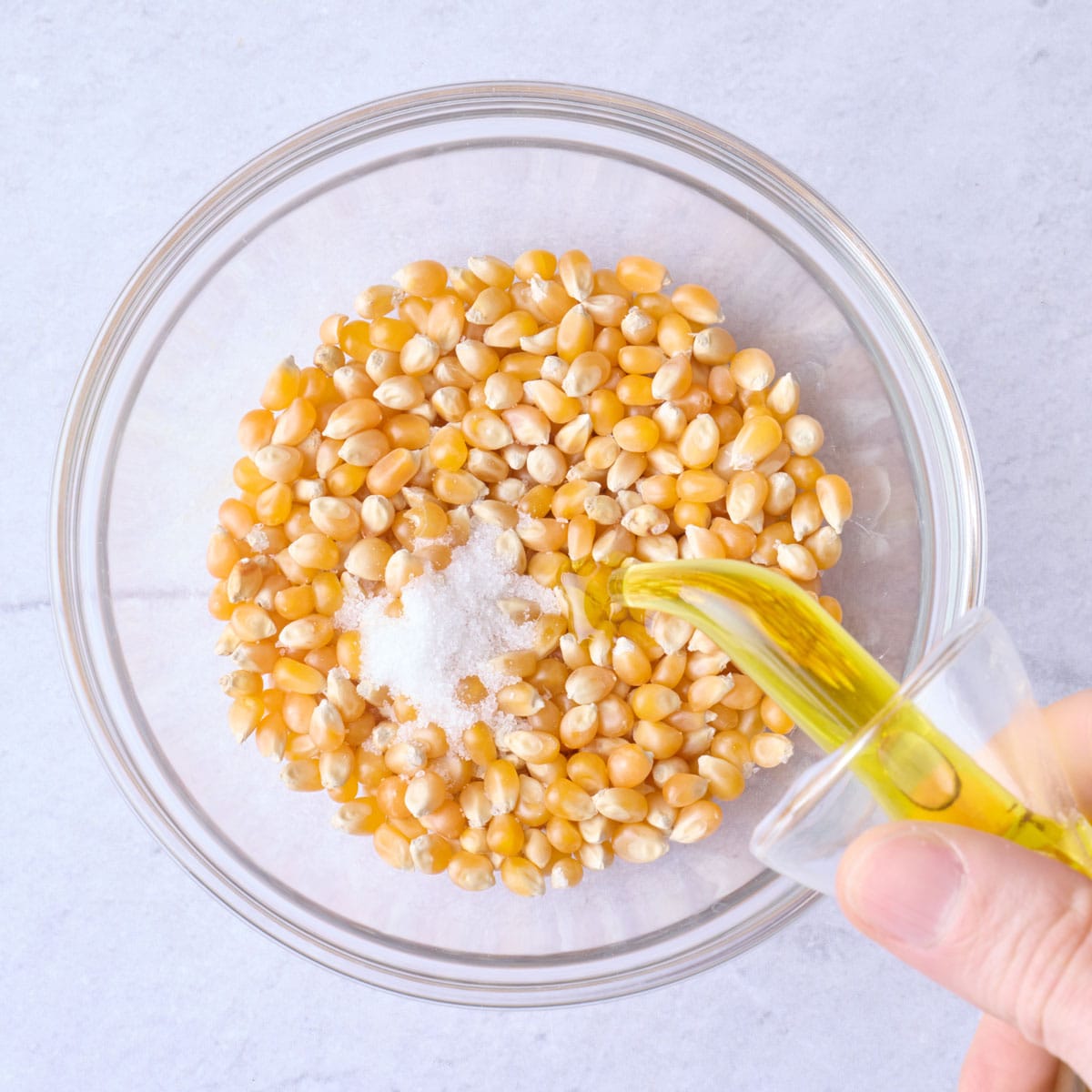 Popcorn kernels, oil, and salt in a small bowl.