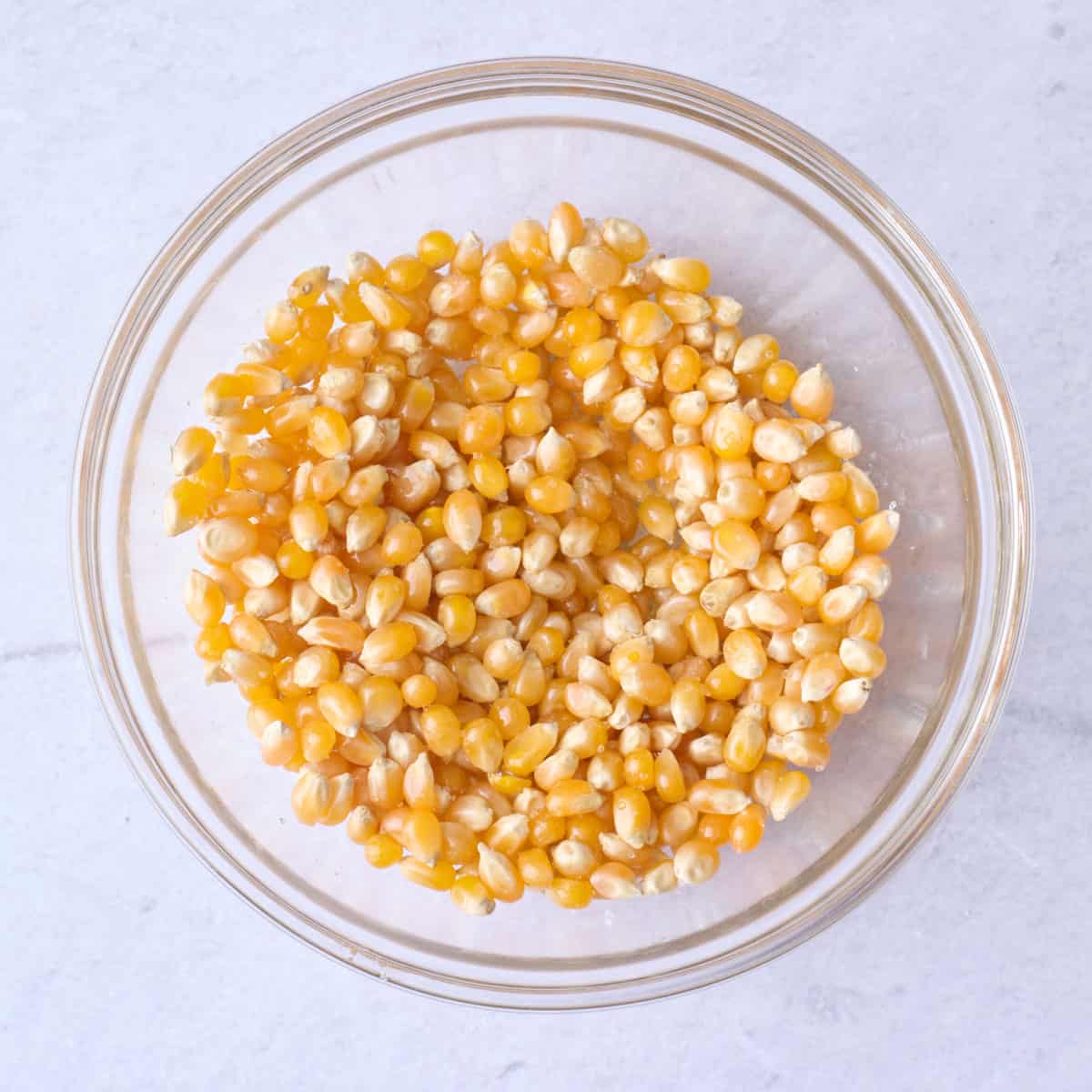 Popcorn kernels, oil, and salt in a small bowl after tossing together.