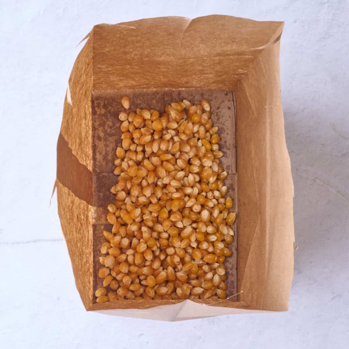 Popcorn kernels in a brown paper bag.