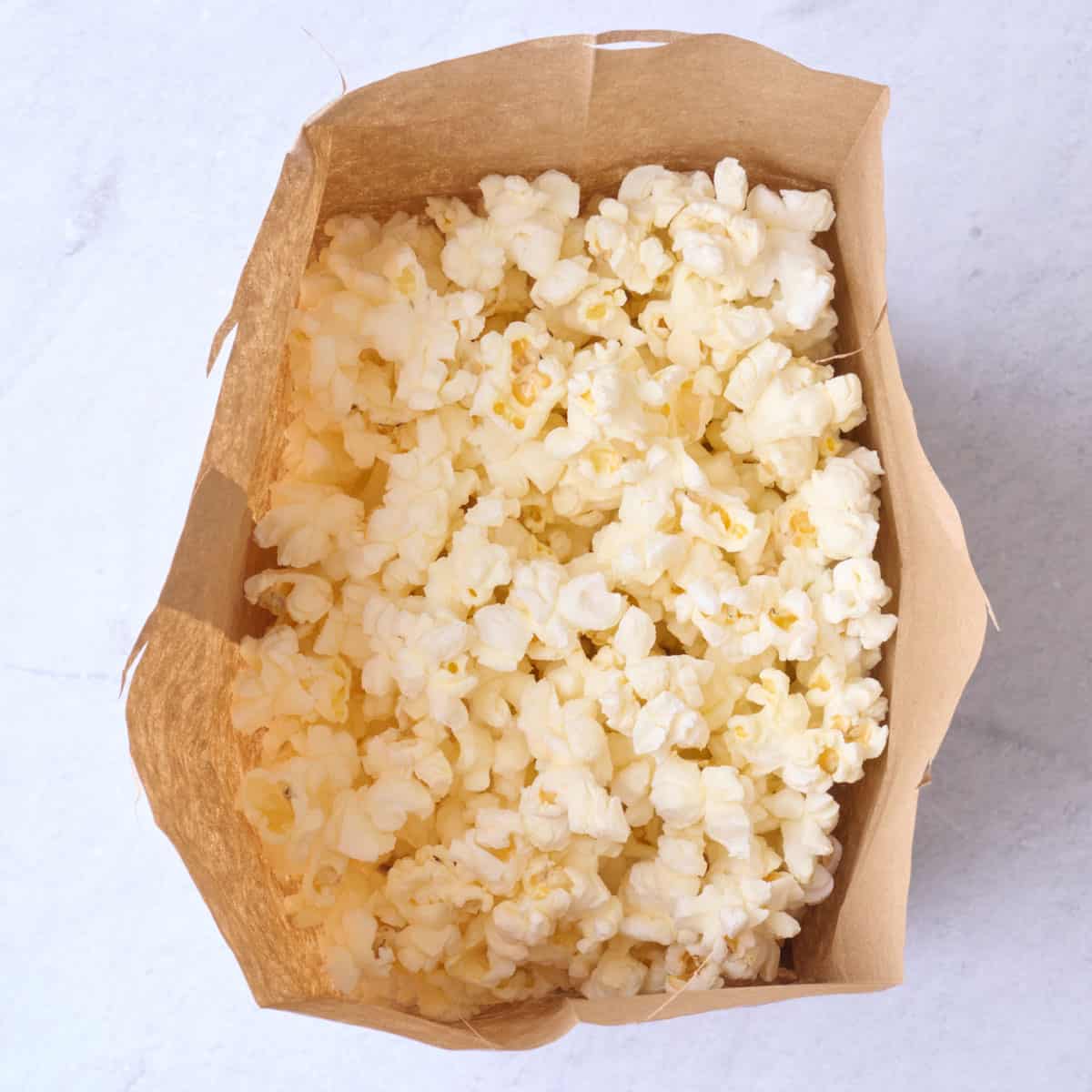 Popcorn after popping in a brown paper bag.