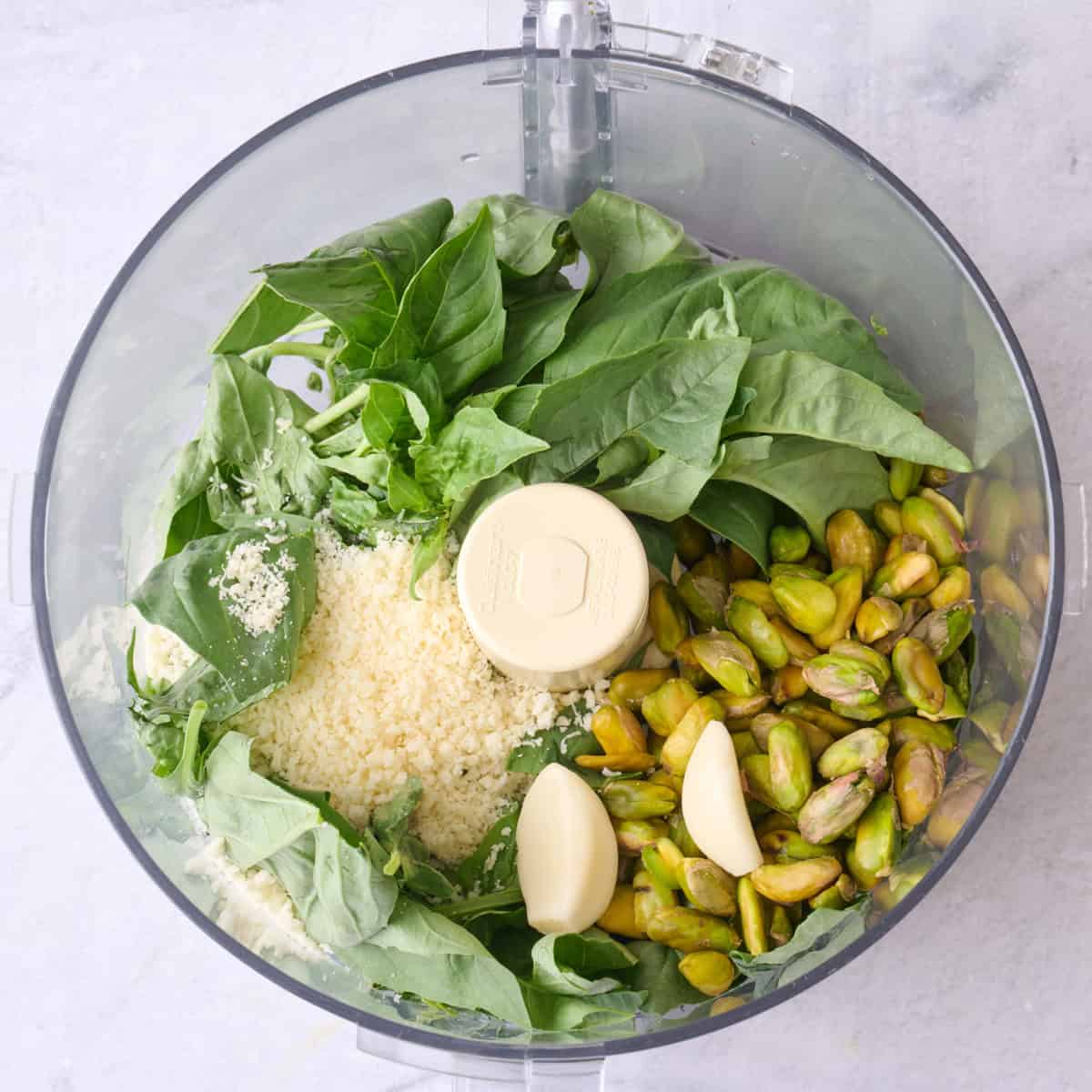 Basil, pistachios, garlic and parmesan in a food processor before pulsing.