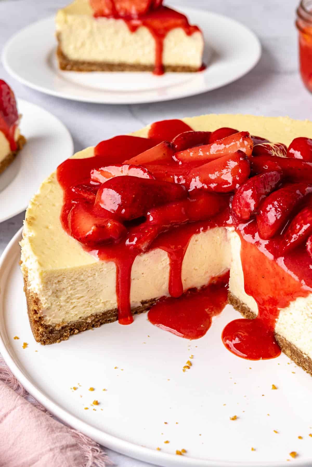 Cheesecake with 2 slices removed to small plates nearby.