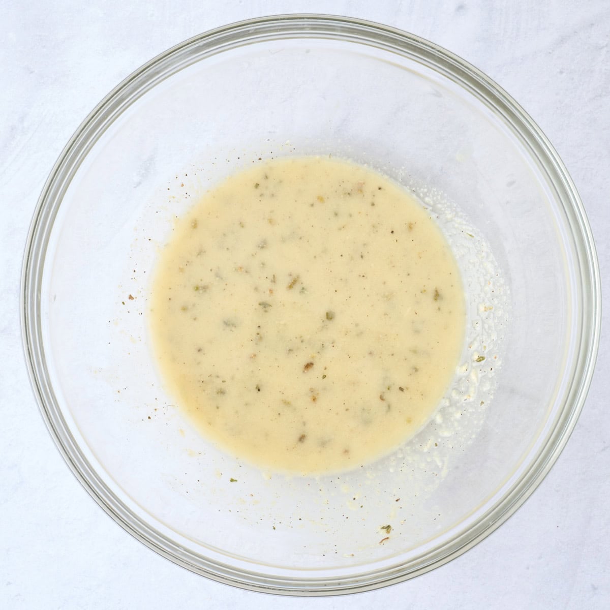 Oil, lemon juice, dijon, and seasonings in a small bowl after mixing.