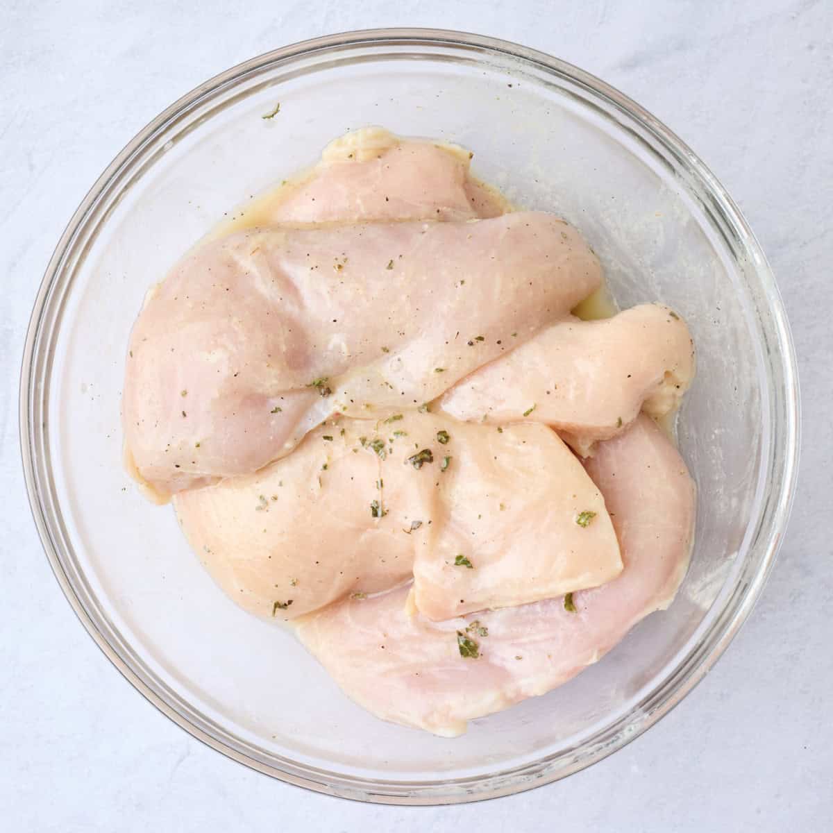 Chicken in a large bowl tossed in ⅓ cup of dressing.