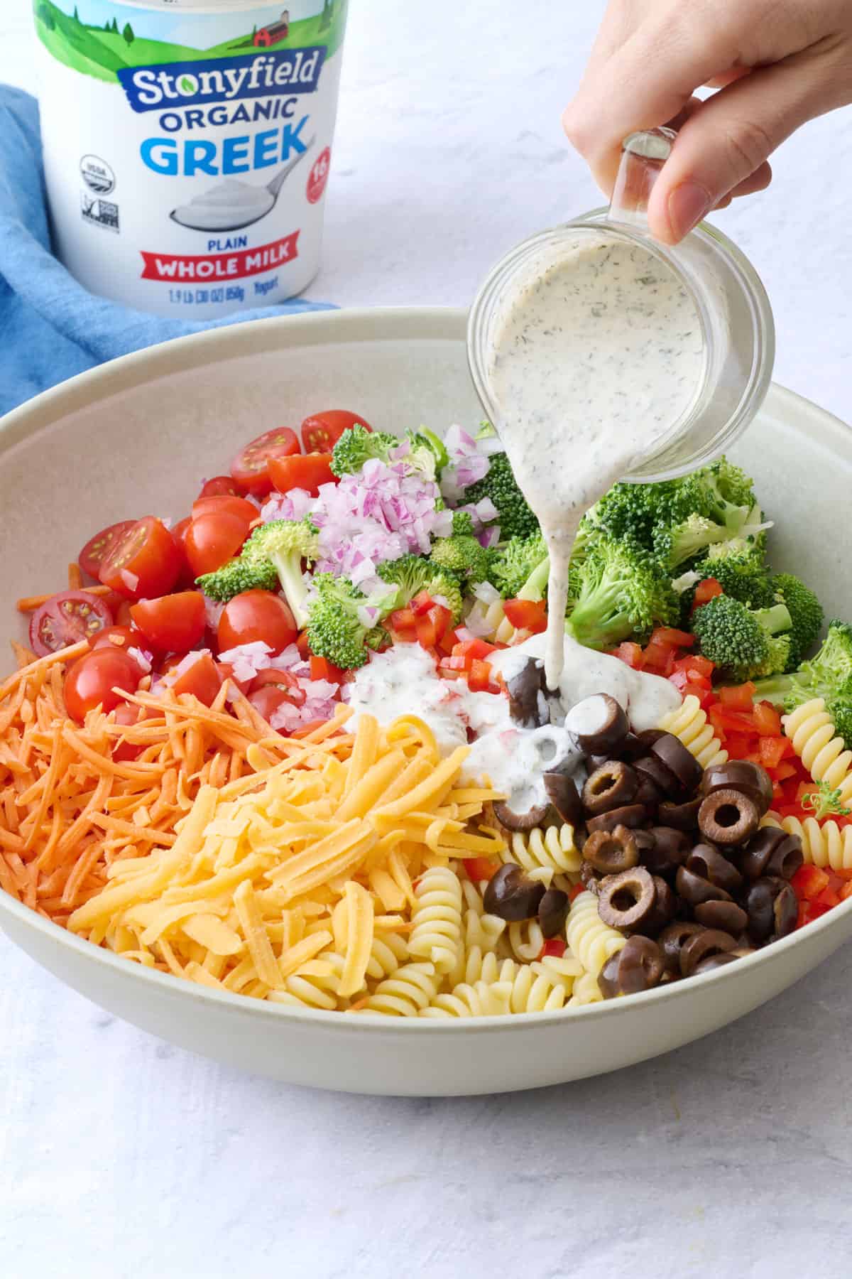 Dressing being poured over salad before tossing together.
