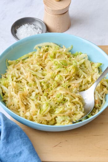 Sauteed cabbage in a shallow bowl with serving set dipped into side.
