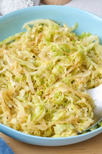 Sauteed cabbage in a shallow bowl with serving set dipped into side.