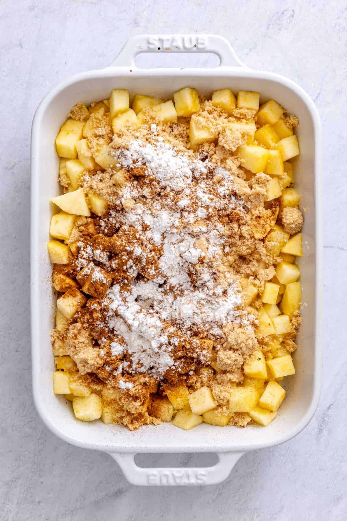 Apples, brown sugar, cornstarch, cinnamon and salt in a baking dish before tossing.