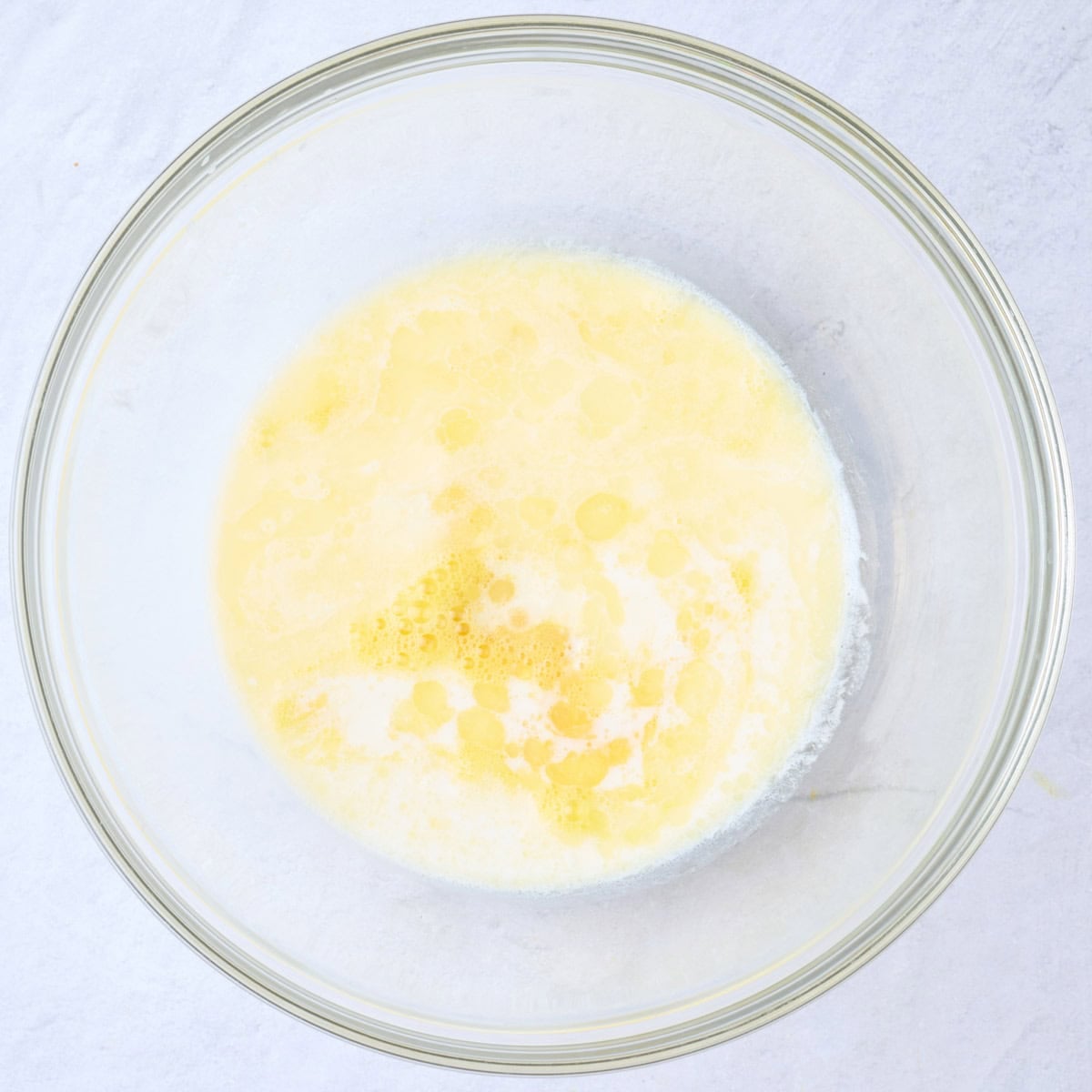 Beaten egg in a large bowl with milk, melted butter and vanilla added before whisking.