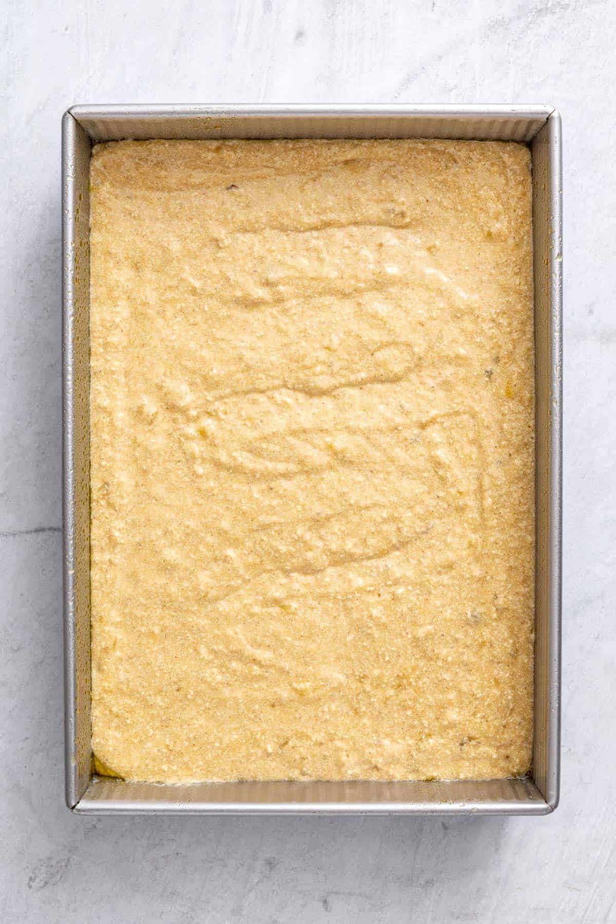 Cake batter added to cake pan before baking.