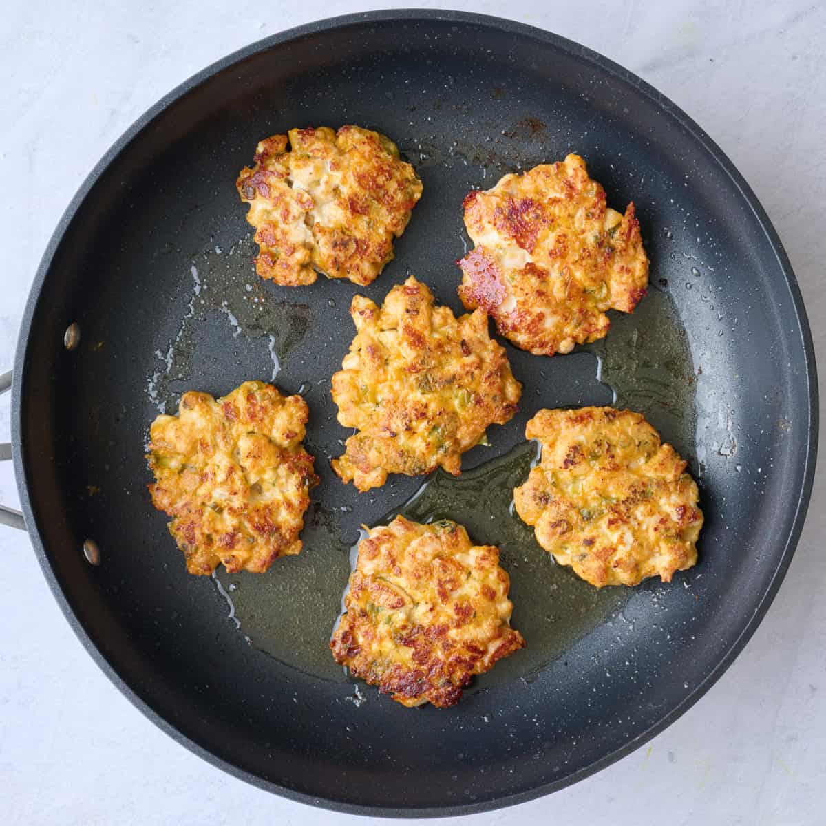 Five fritters in a pan after cooking.