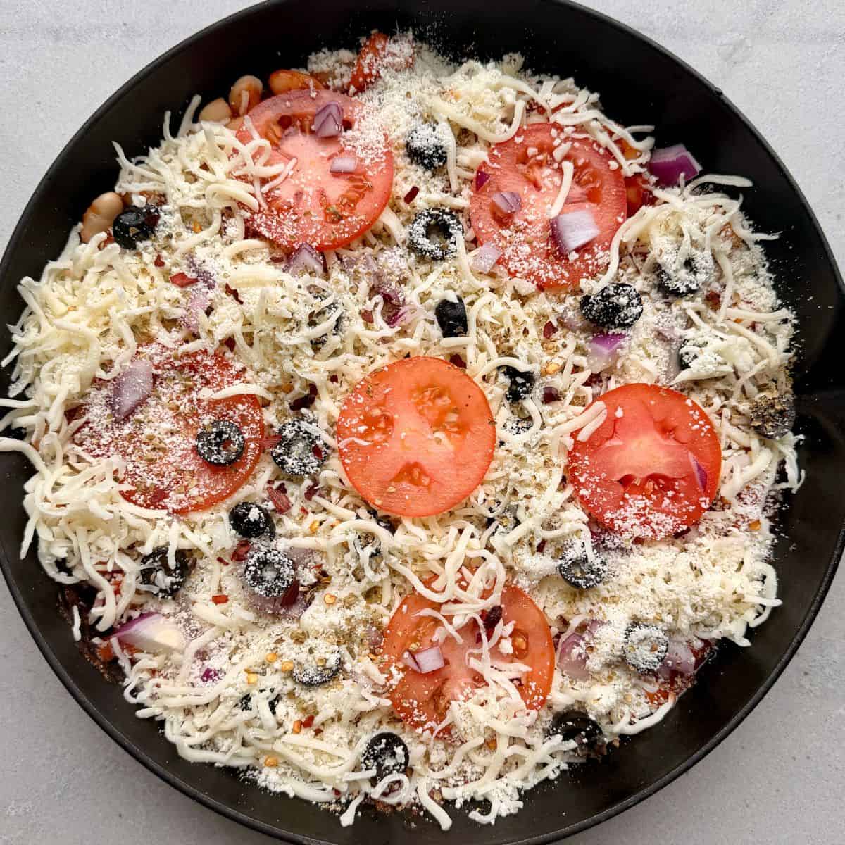 Cheese and pizza toppings added on top of beans.