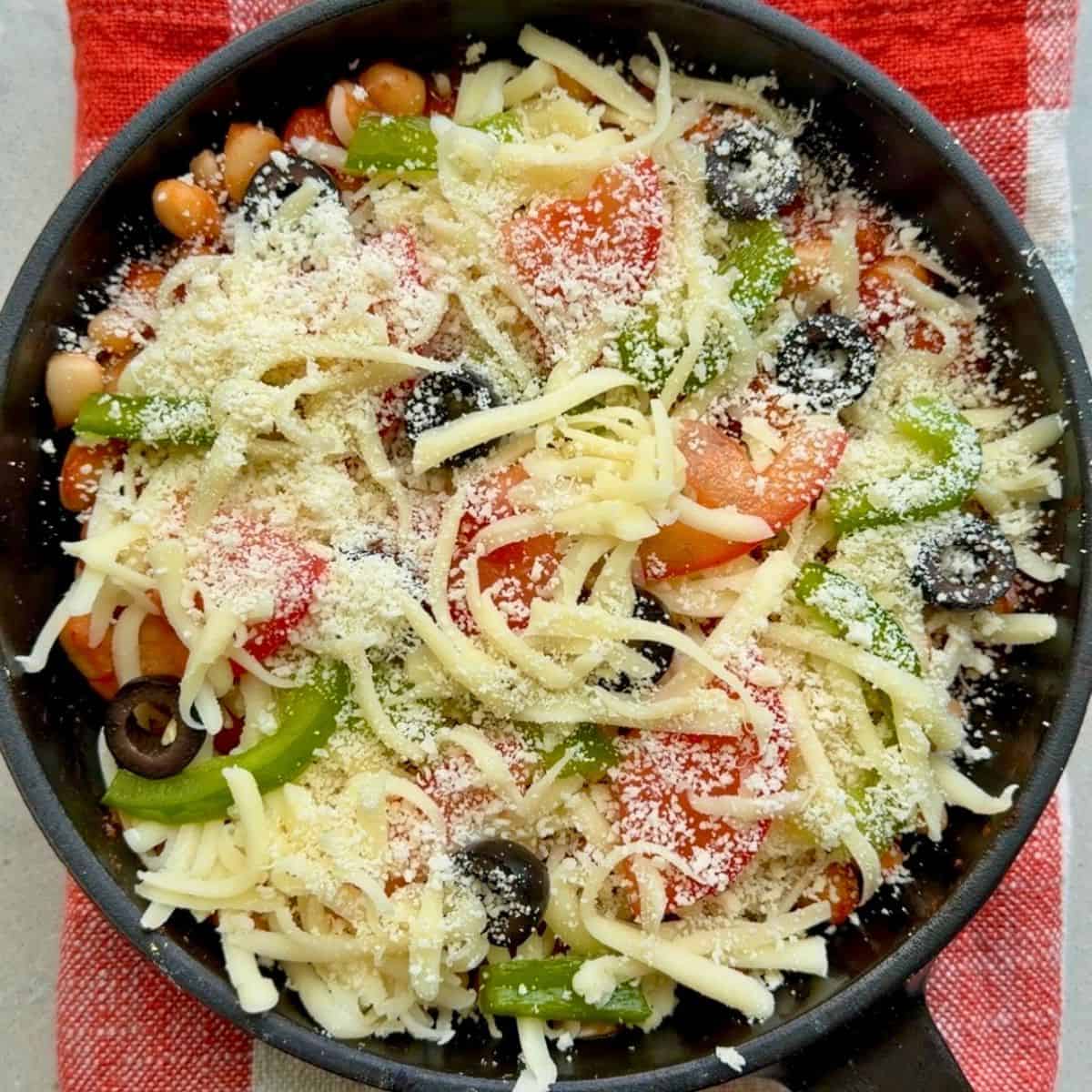 Cheese and pizza toppings added on top of beans.