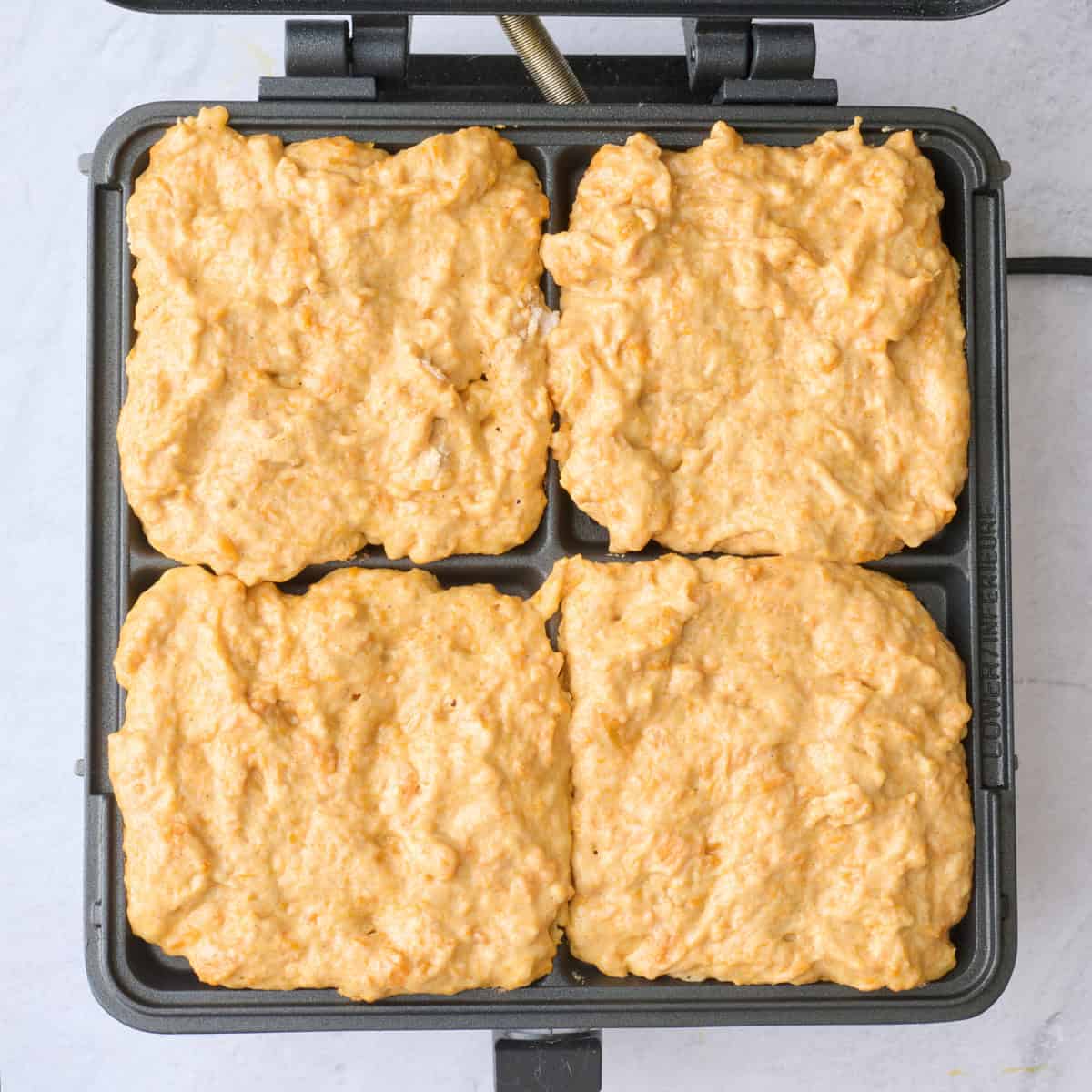 Sweet potato waffle batter in a waffle iron before cooking.