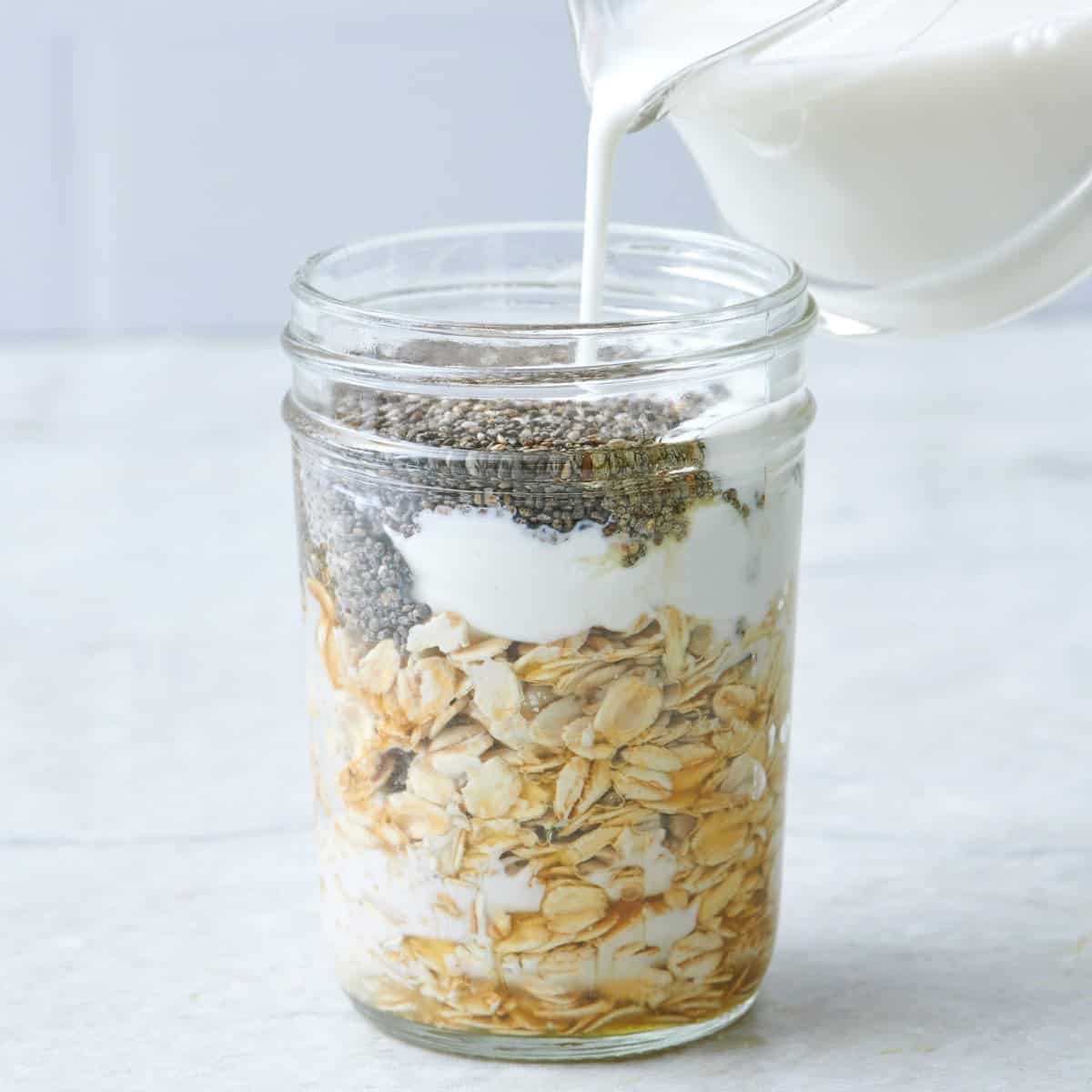 Add milk to overnight oats with chia seeds in a small glass jar.