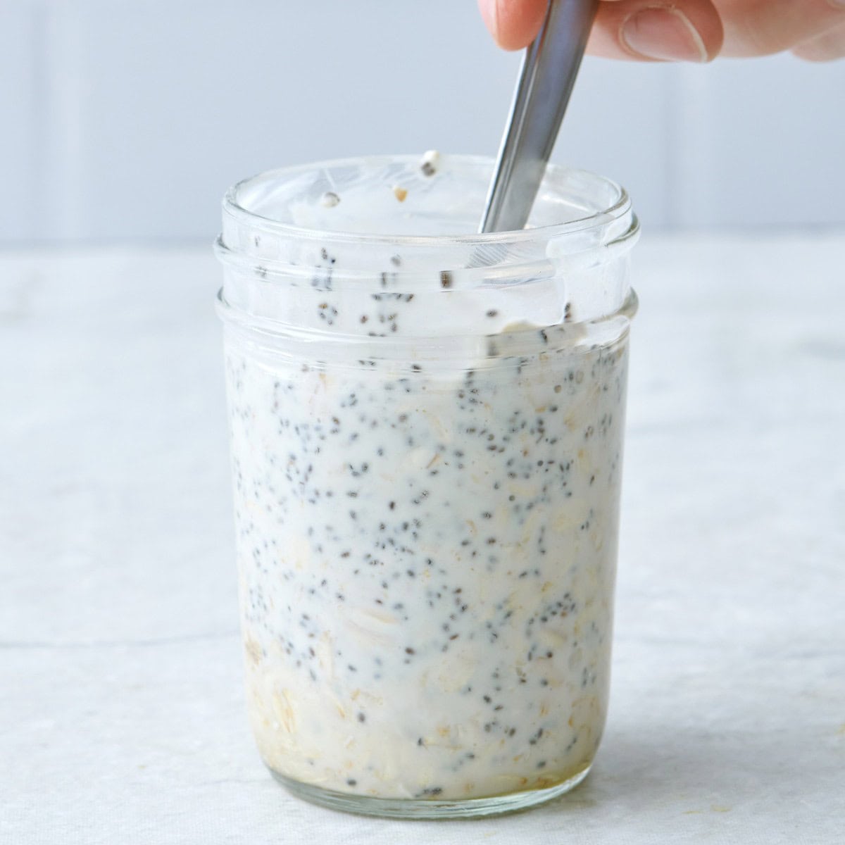 Stirring together rolled oats and chia seed mixture with milk.