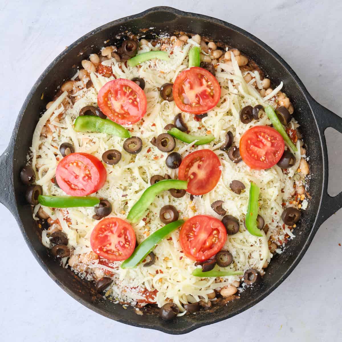 Cheese, tomato, green peppers, olives, and seasoning on top before baking.