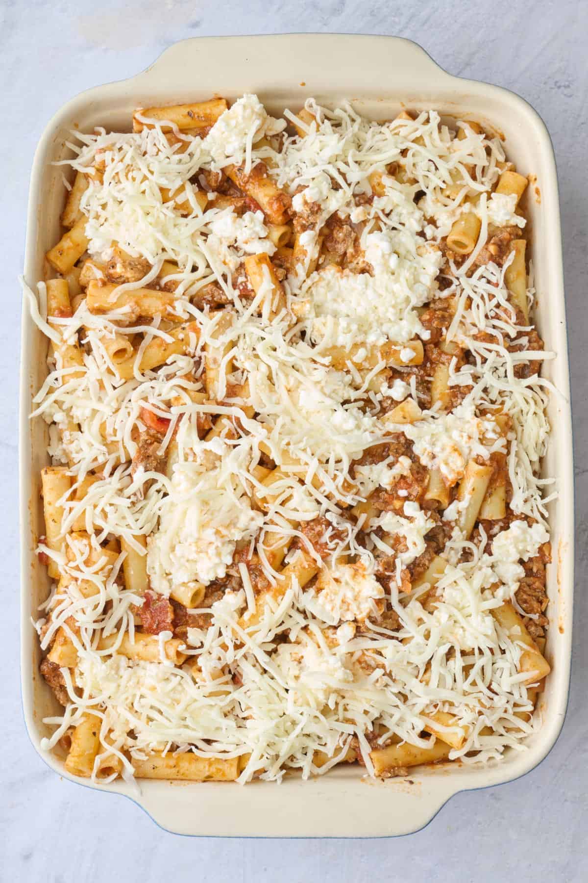 Assembled ziti with mozzarella sprinkled on top before baking.