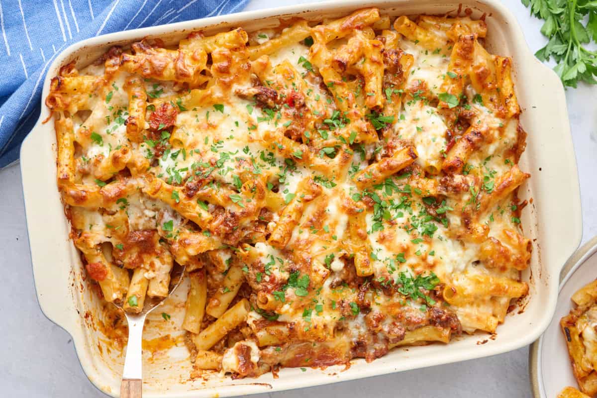 Baked ziti in the baking dish garnished with chopped parsley.
